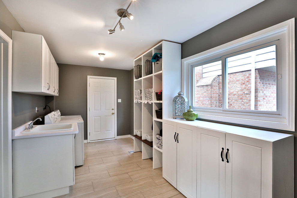 Inspiration for a mid-sized modern u-shaped utility room with an utility sink, shaker cabinets, white cabinets, beige walls and a side-by-side washer and dryer.