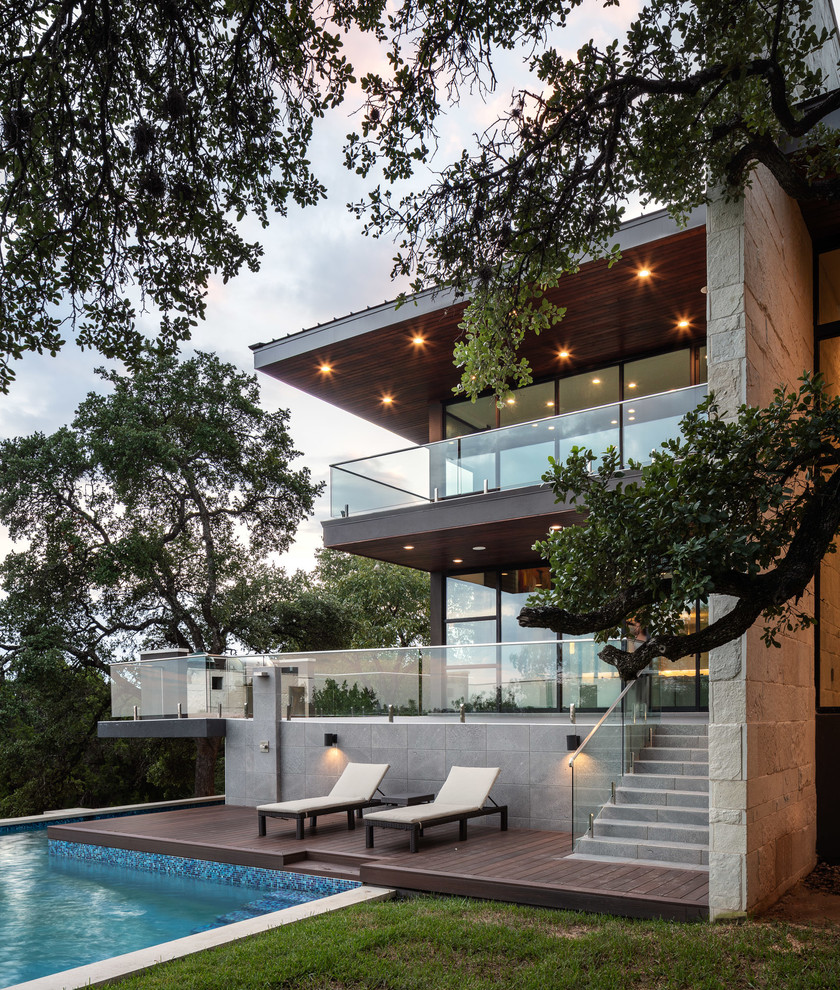 This is an example of a contemporary two-storey glass brown house exterior in Austin with a flat roof.
