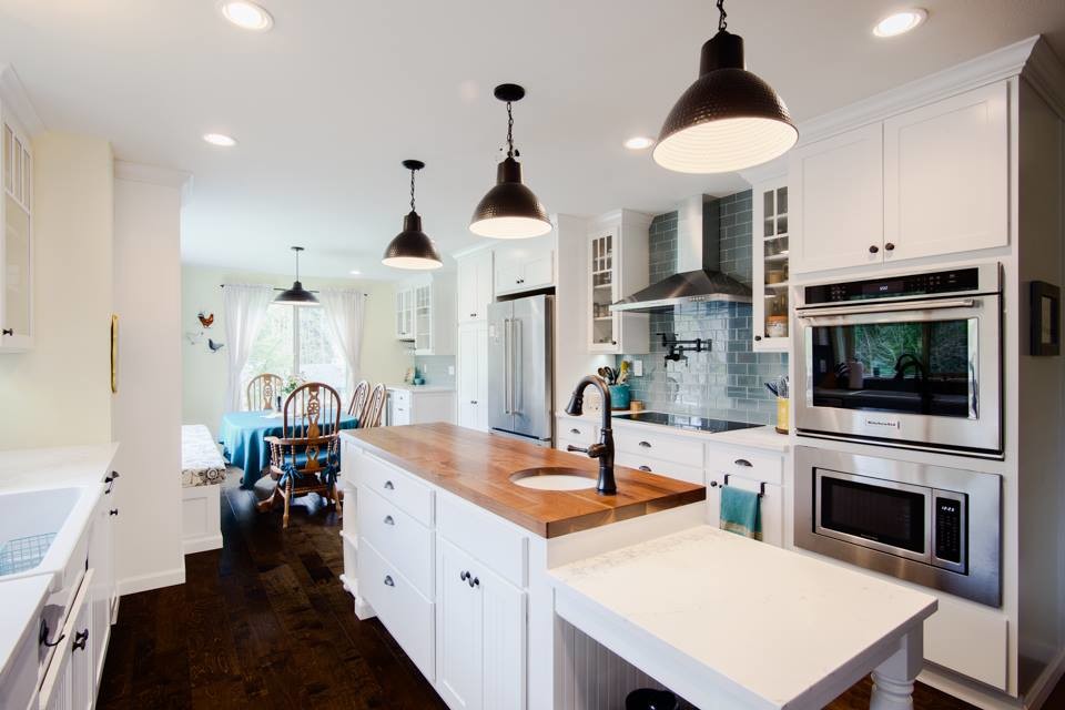 Inspiration for a large country galley open plan kitchen in Seattle with a farmhouse sink, shaker cabinets, white cabinets, quartz benchtops, blue splashback, glass tile splashback, stainless steel appliances, dark hardwood floors, with island and brown floor.