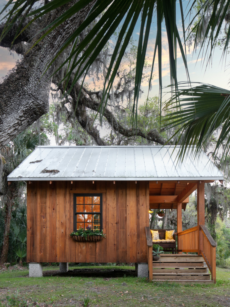 Imagen de fachada marrón y gris campestre pequeña de una planta con revestimiento de madera, tejado a dos aguas, microcasa, tejado de metal y panel y listón