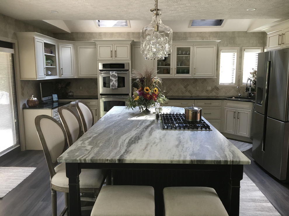 Inspiration for a large transitional u-shaped laminate floor and gray floor eat-in kitchen remodel with an undermount sink, recessed-panel cabinets, white cabinets, granite countertops, white backsplash, ceramic backsplash, stainless steel appliances, an island and black countertops