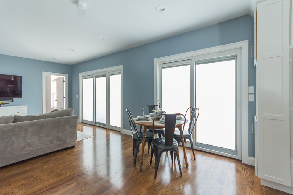 This is an example of a large traditional open concept family room in Boston with blue walls, medium hardwood floors and no fireplace.