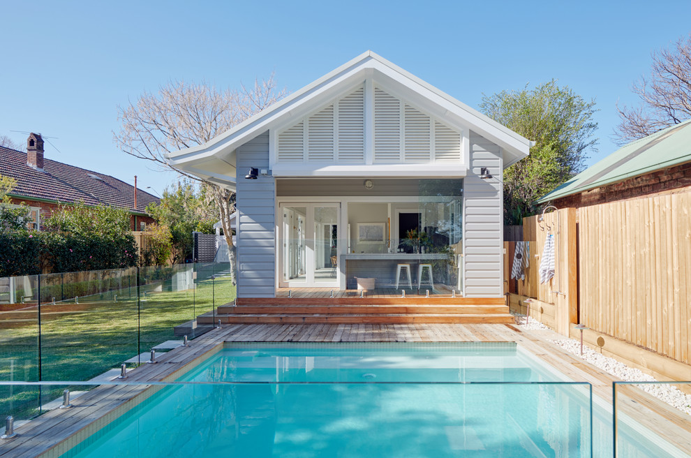 Transitional backyard rectangular pool in Sydney with a pool house and decking.
