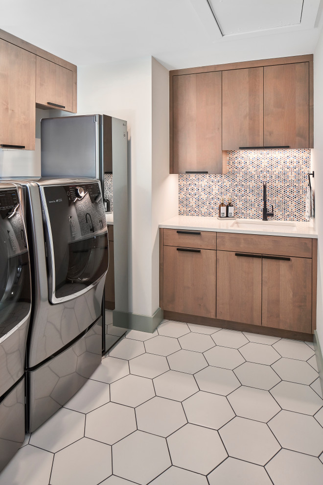 シャーロットにある高級な中くらいなミッドセンチュリースタイルのおしゃれな洗濯室 (L型、アンダーカウンターシンク、フラットパネル扉のキャビネット、中間色木目調キャビネット、クオーツストーンカウンター、マルチカラーのキッチンパネル、セラミックタイルのキッチンパネル、白い壁、セラミックタイルの床、左右配置の洗濯機・乾燥機、白い床、白いキッチンカウンター) の写真