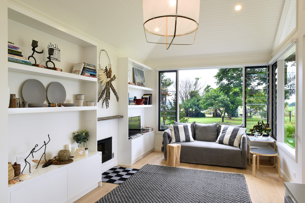 Mid-sized contemporary open concept living room in Wollongong with a library, white walls, medium hardwood floors, a standard fireplace, a plaster fireplace surround and a freestanding tv.