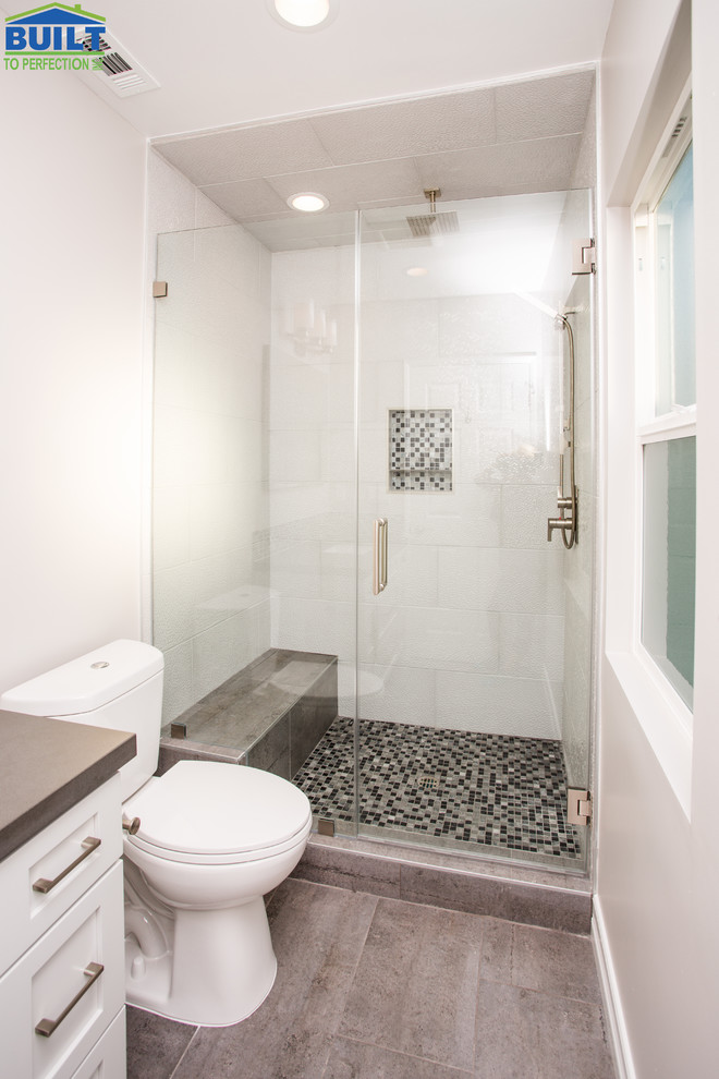 Mid-sized transitional 3/4 bathroom in Los Angeles with shaker cabinets, white cabinets, an alcove shower, a two-piece toilet, blue tile, multi-coloured tile, glass sheet wall, white walls, ceramic floors, an undermount sink, grey floor, a hinged shower door and grey benchtops.