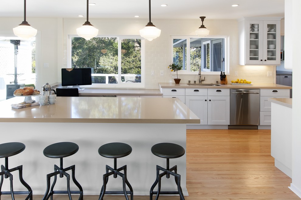 Design ideas for a mid-sized traditional l-shaped separate kitchen in San Francisco with shaker cabinets, subway tile splashback, an undermount sink, white cabinets, white splashback, stainless steel appliances, light hardwood floors and with island.