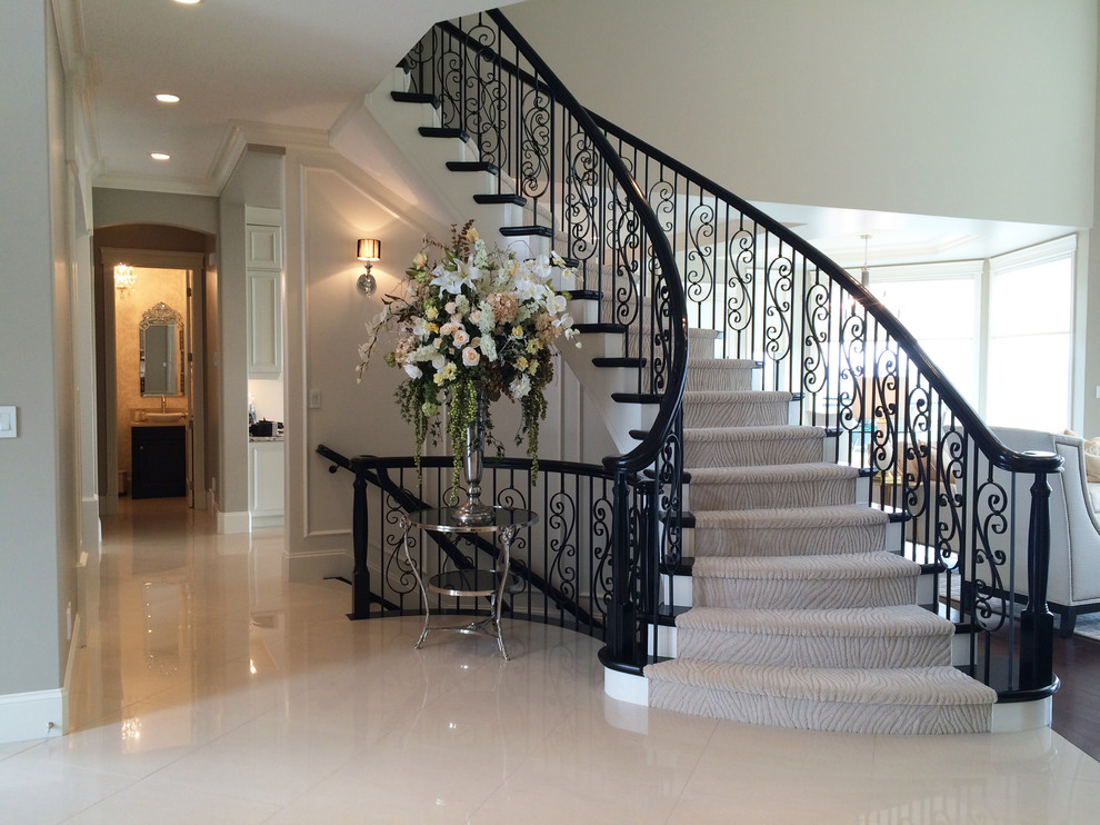 Photo of a large traditional painted wood curved staircase in Edmonton with painted wood risers.
