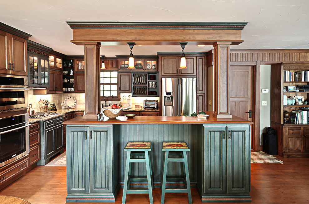 Photo of a large country l-shaped eat-in kitchen in Other with recessed-panel cabinets, stainless steel appliances, wood benchtops, dark wood cabinets, dark hardwood floors and with island.
