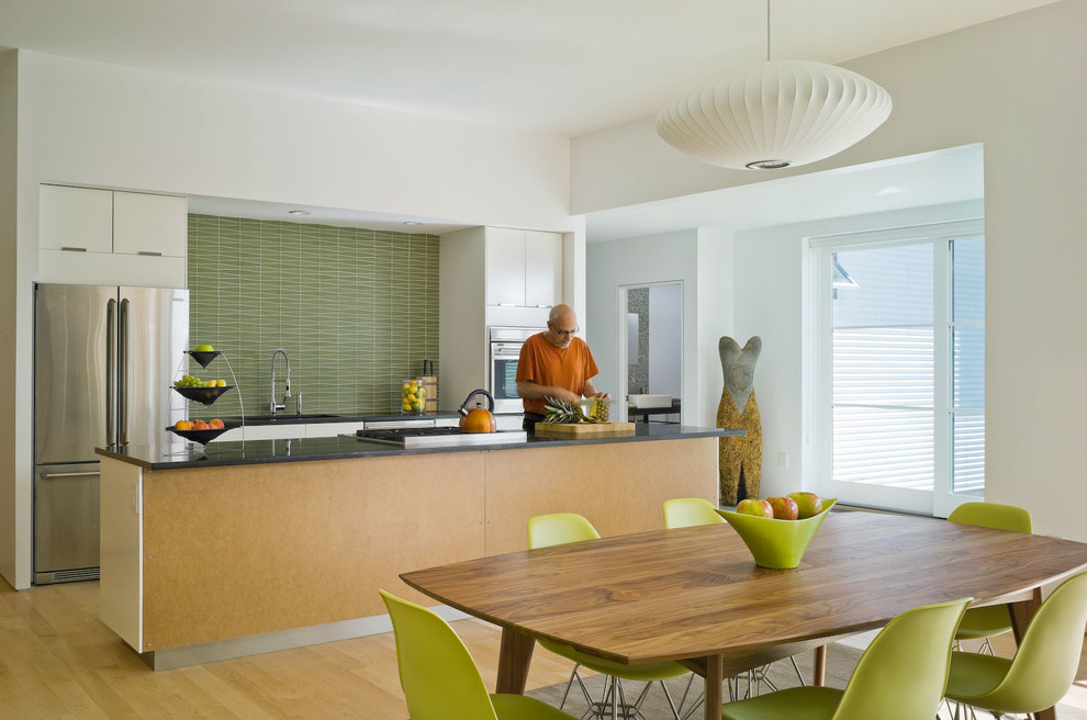 Contemporary galley eat-in kitchen in Burlington with an undermount sink, flat-panel cabinets, white cabinets, green splashback, stainless steel appliances and light hardwood floors.