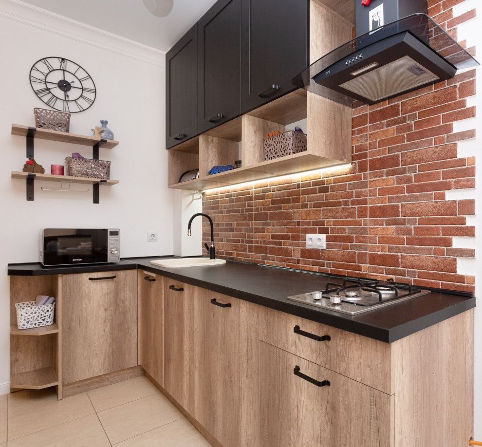 Inspiration for a small country l-shaped kitchen in Other with a farmhouse sink, raised-panel cabinets, grey cabinets, wood benchtops, black splashback, brick splashback, black appliances, ceramic floors, no island and brown floor.