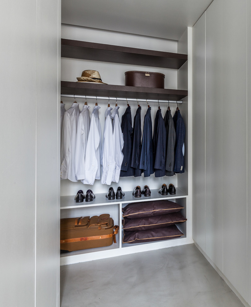 Photo of a mid-sized contemporary men's walk-in wardrobe in Paris with open cabinets, concrete floors, white cabinets and grey floor.