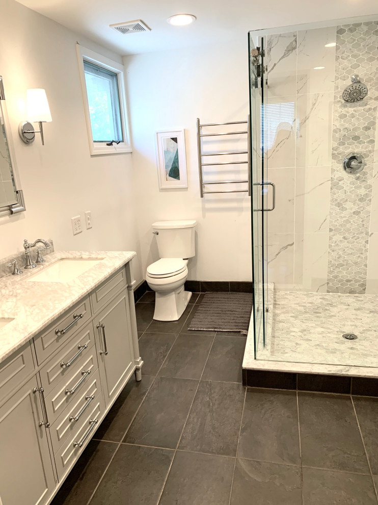 Inspiration for a medium sized classic ensuite bathroom in Detroit with shaker cabinets, grey cabinets, a corner shower, a two-piece toilet, white tiles, porcelain tiles, white walls, porcelain flooring, a submerged sink, marble worktops, grey floors, a sliding door, white worktops, a wall niche, double sinks and a freestanding vanity unit.