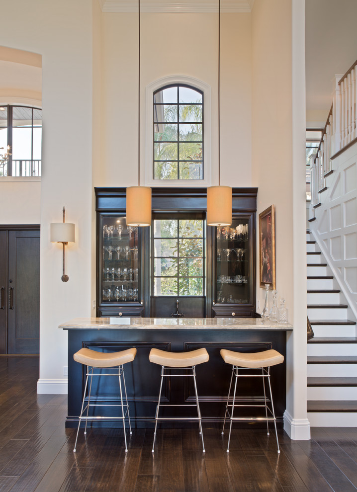Photo of a transitional seated home bar in Miami with recessed-panel cabinets, black cabinets and dark hardwood floors.
