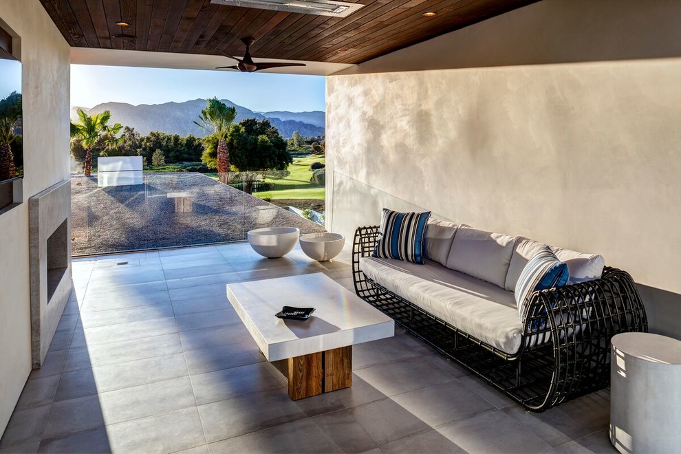 This is an example of a contemporary patio in Los Angeles with concrete pavers, a roof extension and with fireplace.