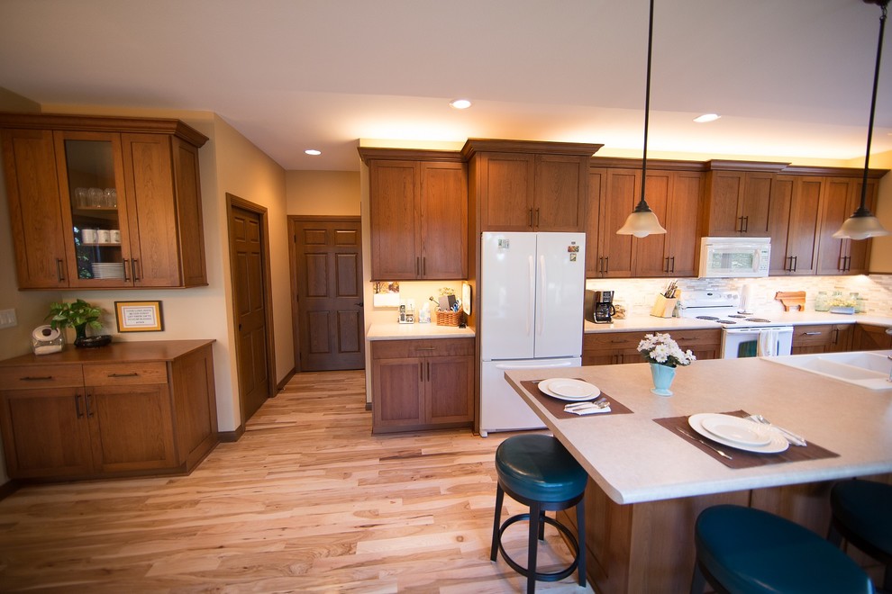 Inspiration for a large transitional l-shaped light wood floor eat-in kitchen remodel in Cedar Rapids with a double-bowl sink, recessed-panel cabinets, medium tone wood cabinets, laminate countertops, multicolored backsplash, mosaic tile backsplash, white appliances and an island