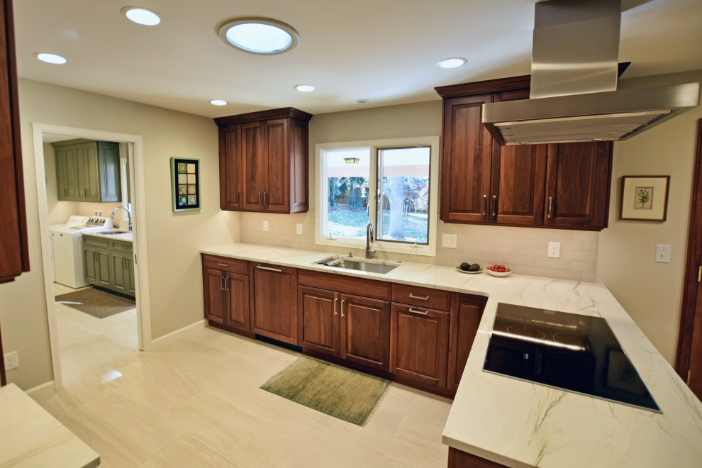 Large traditional u-shaped eat-in kitchen in Denver with an undermount sink, raised-panel cabinets, dark wood cabinets, stainless steel appliances and white benchtop.