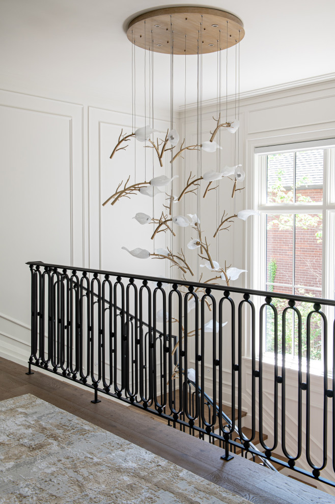 Example of a large transitional wooden u-shaped metal railing and wall paneling staircase design in Toronto with wooden risers
