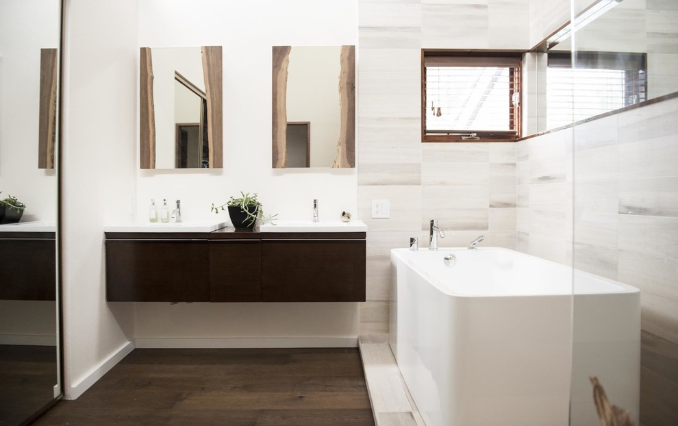Photo of a large country master bathroom in Denver with flat-panel cabinets, medium wood cabinets, a freestanding tub, a curbless shower, a wall-mount toilet, white tile, stone tile, white walls, dark hardwood floors, a drop-in sink, brown floor, an open shower and white benchtops.