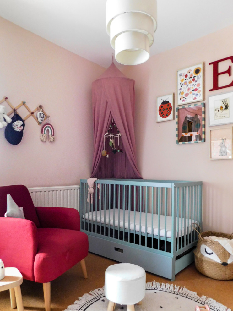This is an example of a small classic nursery for girls in Hertfordshire with pink walls and cork flooring.