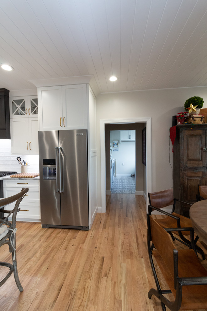 Example of a large l-shaped eat-in kitchen design with shaker cabinets, white cabinets, granite countertops, an island and white countertops
