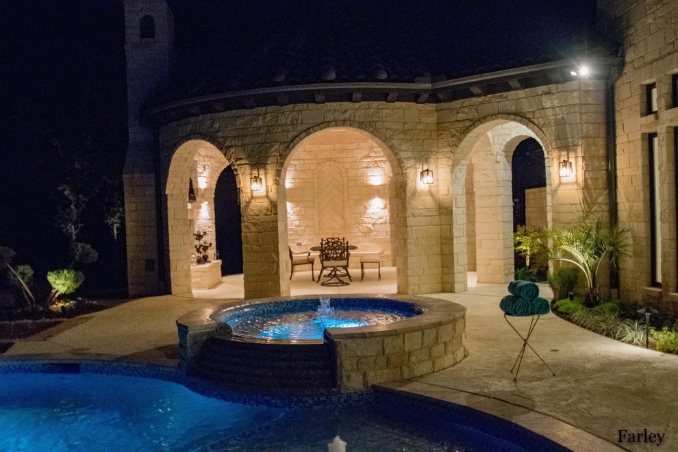 Mid-sized contemporary backyard custom-shaped pool in Dallas with a water feature and natural stone pavers.