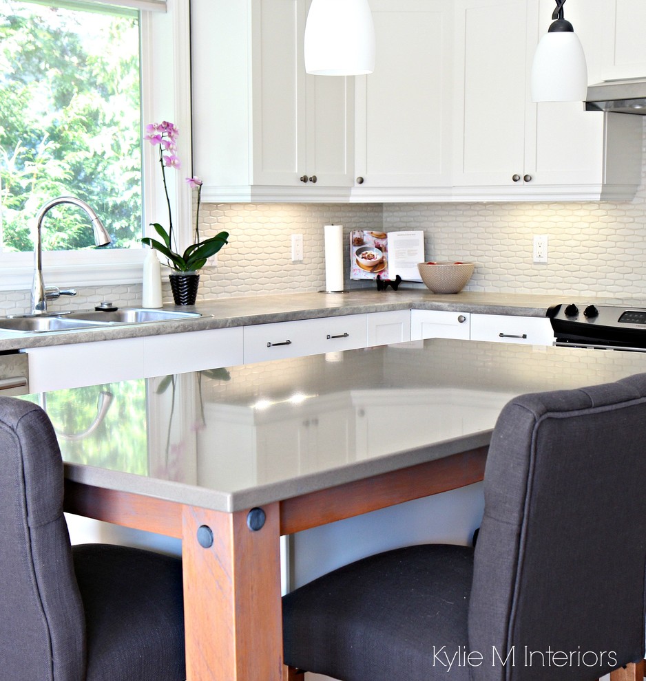 Mid-sized transitional l-shaped light wood floor open concept kitchen photo in Vancouver with a drop-in sink, shaker cabinets, white cabinets, quartz countertops, white backsplash, porcelain backsplash, stainless steel appliances and an island