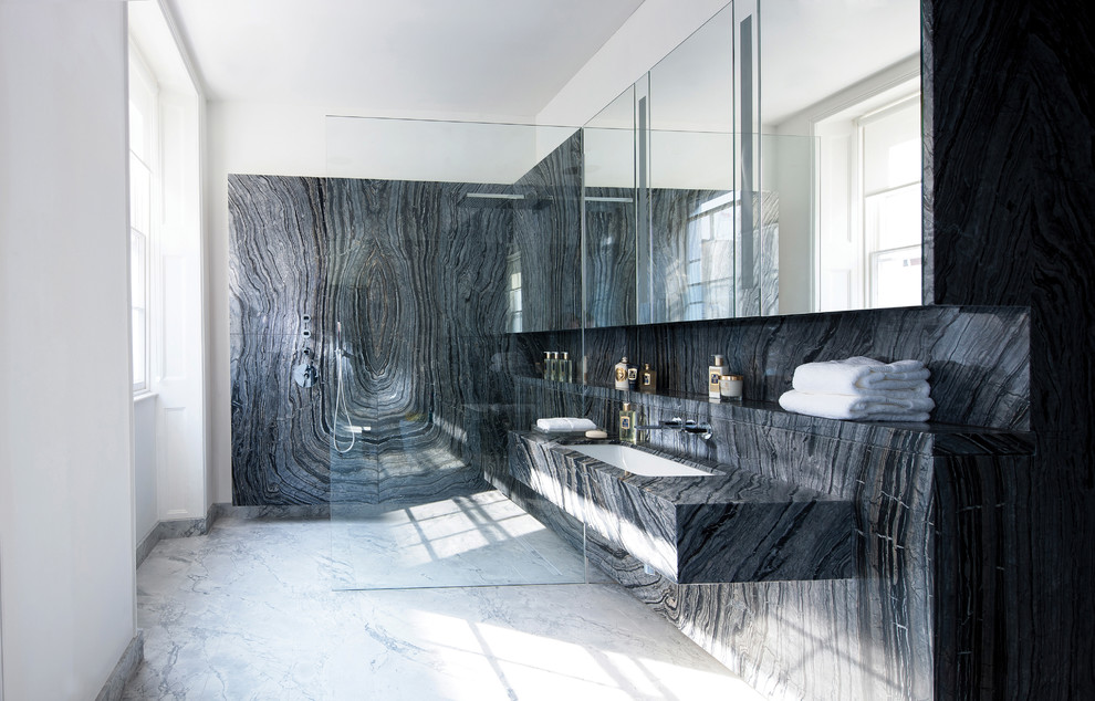 Design ideas for a large modern master bathroom in London with glass-front cabinets, grey cabinets, a drop-in tub, a curbless shower, a wall-mount toilet, black tile, stone slab, black walls, marble floors, a drop-in sink, marble benchtops, grey floor and an open shower.