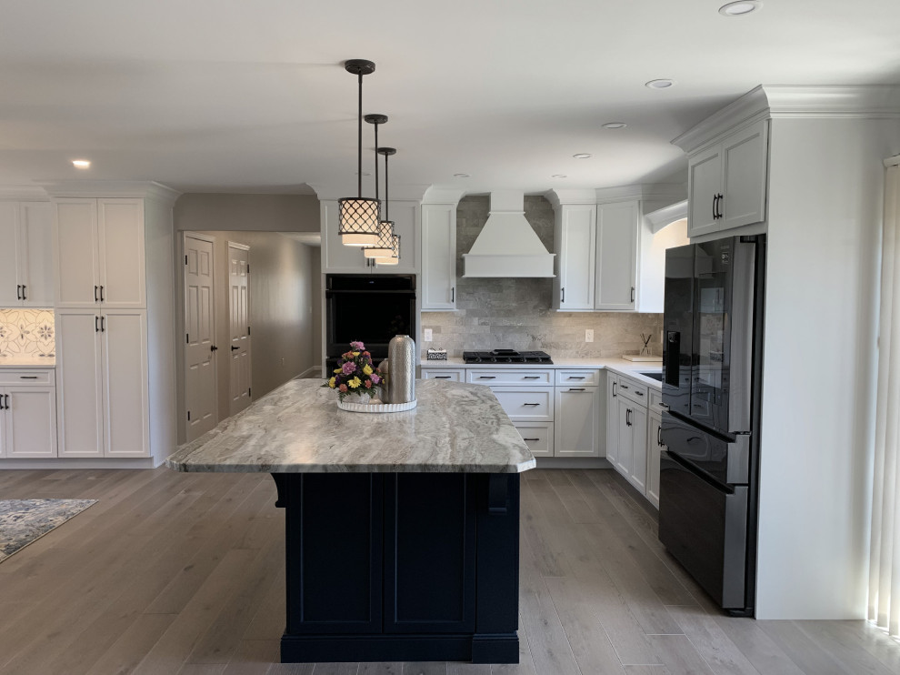 Inspiration for a large transitional l-shaped vinyl floor and gray floor eat-in kitchen remodel with an undermount sink, recessed-panel cabinets, white cabinets, quartz countertops, gray backsplash, ceramic backsplash, stainless steel appliances, an island and white countertops