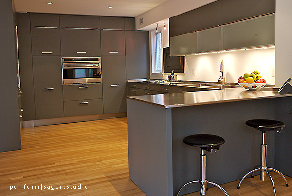 Photo of a contemporary l-shaped eat-in kitchen in DC Metro with an integrated sink, flat-panel cabinets, dark wood cabinets, quartz benchtops, white splashback and stainless steel appliances.