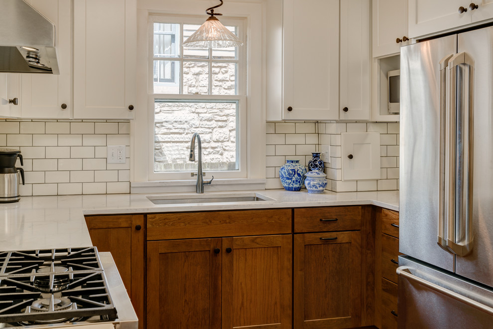Inspiration for a small traditional u-shaped separate kitchen in Columbus with a single-bowl sink, shaker cabinets, medium wood cabinets, granite benchtops, white splashback, subway tile splashback, stainless steel appliances, medium hardwood floors, a peninsula and white benchtop.
