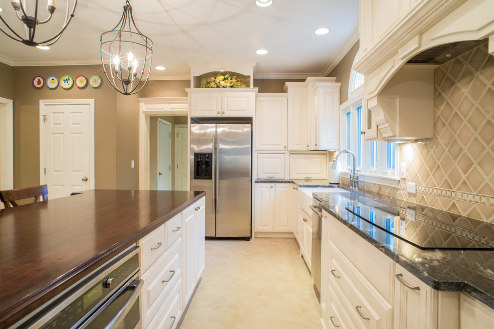Inspiration for a large traditional l-shaped separate kitchen in Indianapolis with a farmhouse sink, raised-panel cabinets, white cabinets, granite benchtops, beige splashback, ceramic splashback, stainless steel appliances, travertine floors and with island.