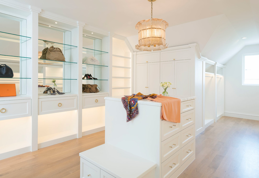 Inspiration for a mediterranean women's walk-in wardrobe in Dallas with shaker cabinets, white cabinets, light hardwood floors and beige floor.