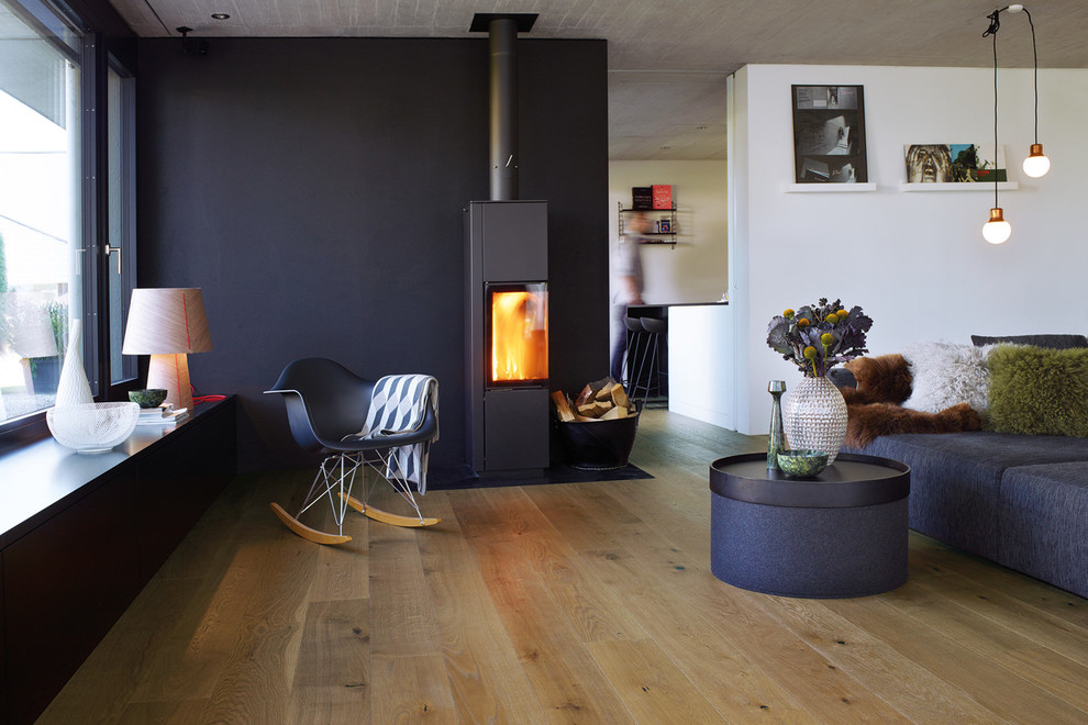 This is an example of a mid-sized contemporary enclosed family room in Dusseldorf with white walls, medium hardwood floors, a wood stove, a metal fireplace surround, no tv and brown floor.