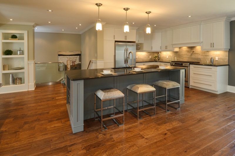 This is an example of a large transitional l-shaped eat-in kitchen in Burlington with an undermount sink, shaker cabinets, white cabinets, soapstone benchtops, beige splashback, stone tile splashback, stainless steel appliances, medium hardwood floors and with island.