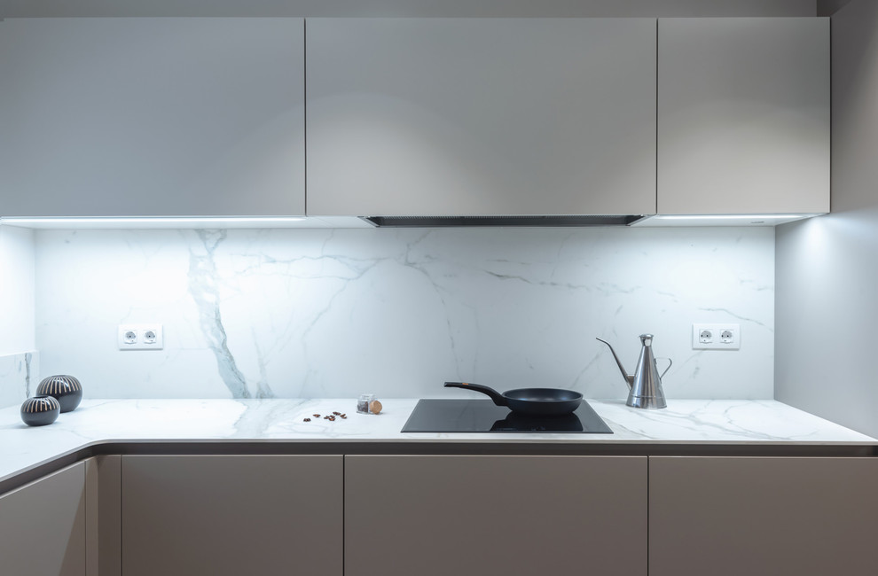 This is an example of a mid-sized contemporary u-shaped separate kitchen in Barcelona with a drop-in sink, flat-panel cabinets, grey cabinets, white splashback, panelled appliances, no island and white benchtop.