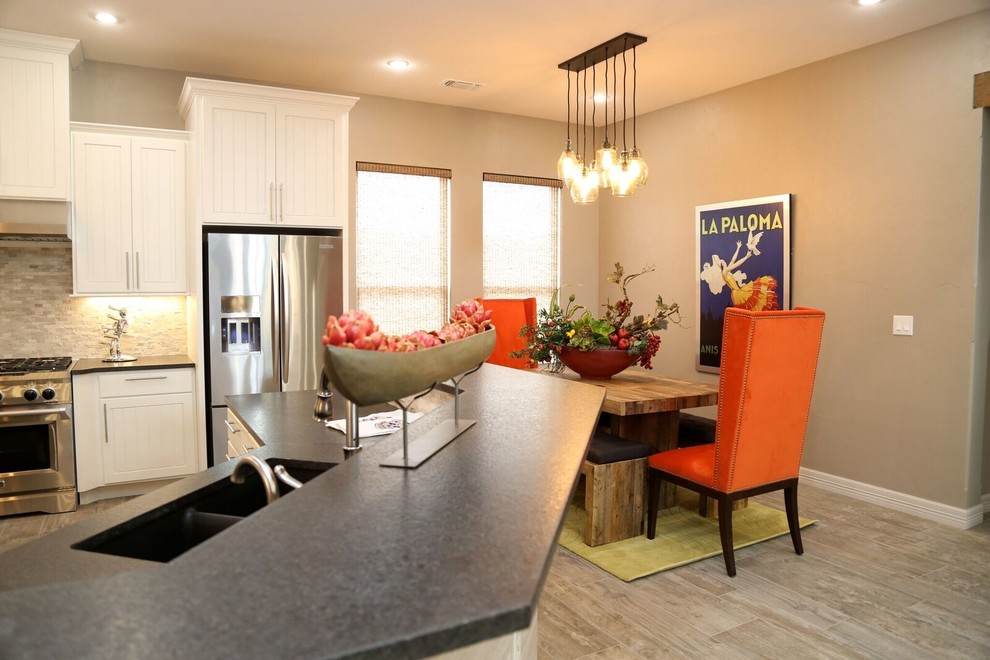 Small transitional u-shaped light wood floor eat-in kitchen photo in Orange County with an undermount sink, louvered cabinets, white cabinets, solid surface countertops, beige backsplash, stone tile backsplash, stainless steel appliances and two islands