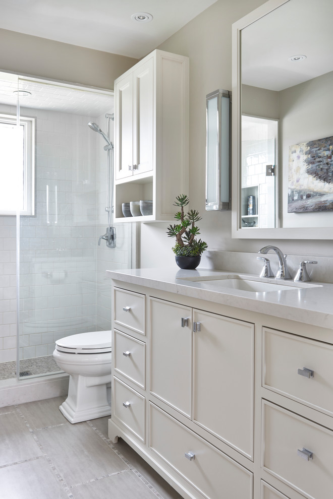 Inspiration for a mid-sized traditional bathroom in Toronto with beige cabinets, an alcove shower, a two-piece toilet, white tile, ceramic tile, beige walls, ceramic floors, an undermount sink, engineered quartz benchtops, beige floor, a hinged shower door and recessed-panel cabinets.