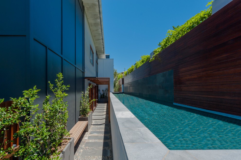 Photo of a large contemporary courtyard rectangular lap pool in Brisbane with natural stone pavers.