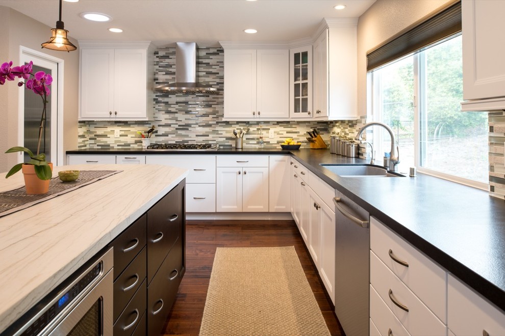 Inspiration for a large modern u-shaped medium tone wood floor eat-in kitchen remodel in San Diego with a drop-in sink, recessed-panel cabinets, white cabinets, granite countertops, multicolored backsplash and stainless steel appliances