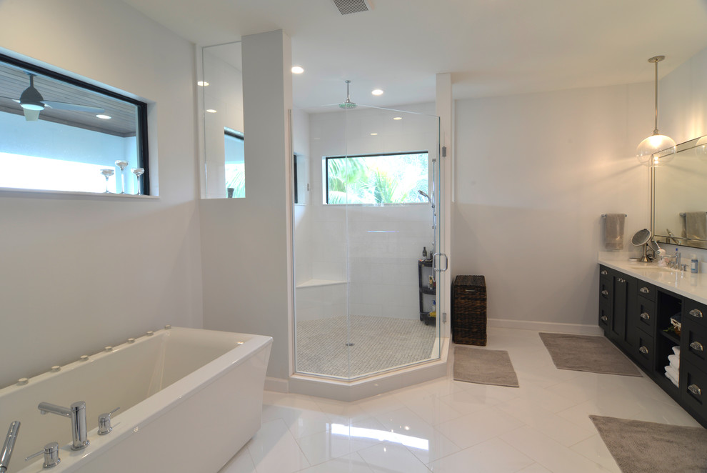 Design ideas for a mid-sized contemporary master bathroom in Miami with recessed-panel cabinets, brown cabinets, a freestanding tub, a corner shower, a one-piece toilet, white tile, marble, white walls, porcelain floors, an integrated sink, engineered quartz benchtops, white floor and a hinged shower door.