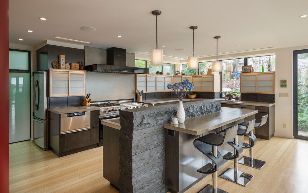 Photo of an asian l-shaped open plan kitchen in Seattle with a single-bowl sink, flat-panel cabinets, dark wood cabinets, concrete benchtops, grey splashback, stainless steel appliances, bamboo floors and with island.