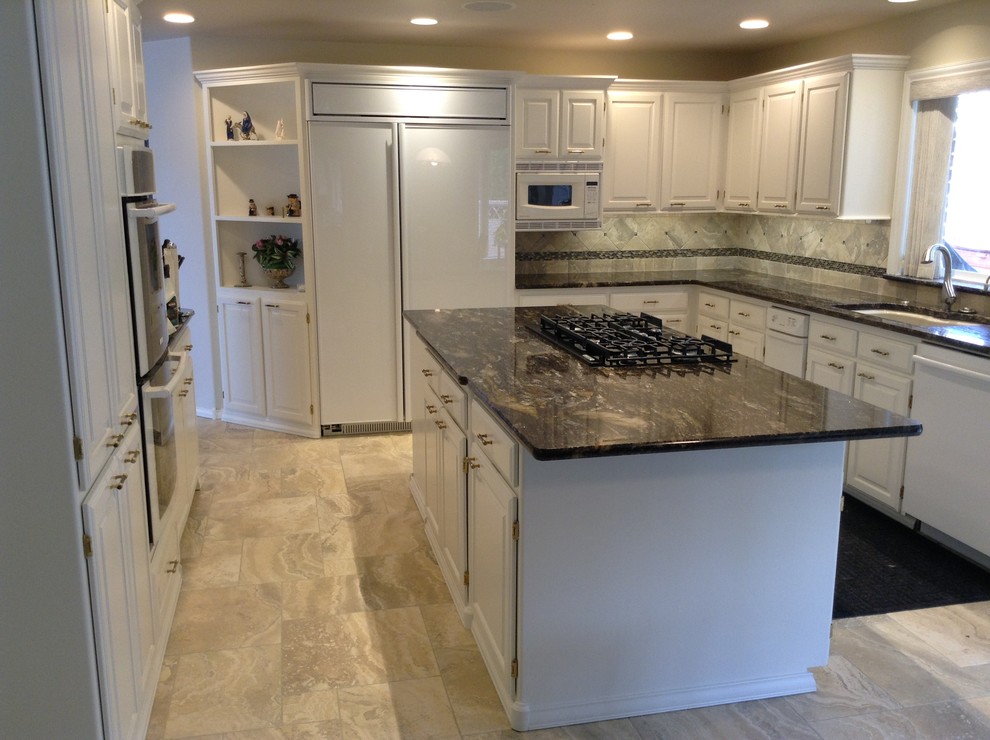 Inspiration for a mid-sized transitional u-shaped travertine floor enclosed kitchen remodel in Seattle with an undermount sink, raised-panel cabinets, white cabinets, granite countertops, gray backsplash, porcelain backsplash, stainless steel appliances and an island