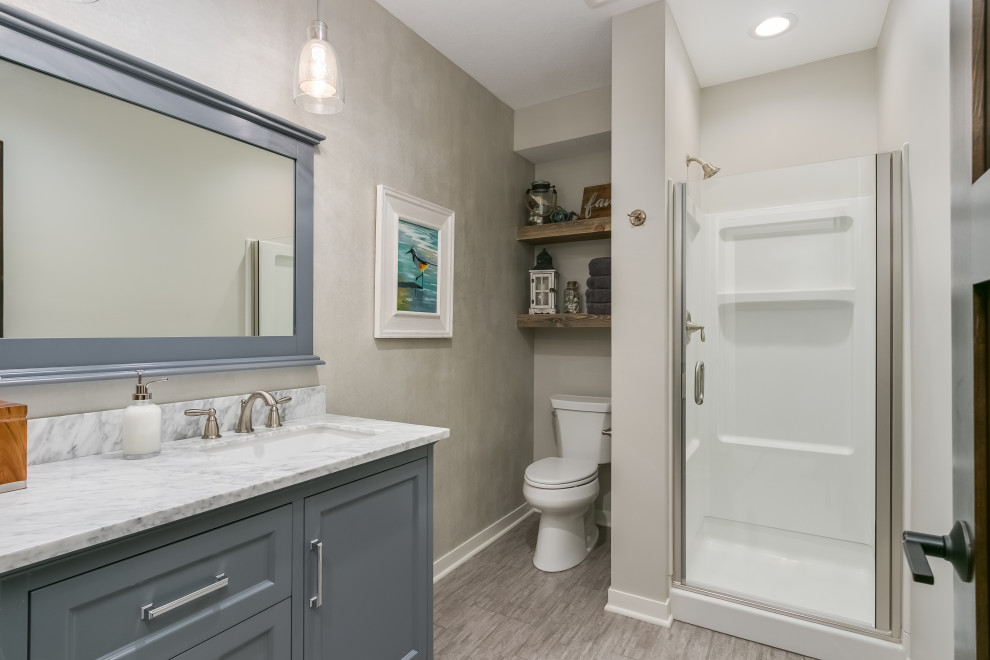 This is an example of a mid-sized beach style master bathroom in Minneapolis with flat-panel cabinets, grey cabinets, an alcove shower, a one-piece toilet, beige tile, beige walls, a drop-in sink, marble benchtops, a hinged shower door, multi-coloured benchtops, a single vanity and a floating vanity.