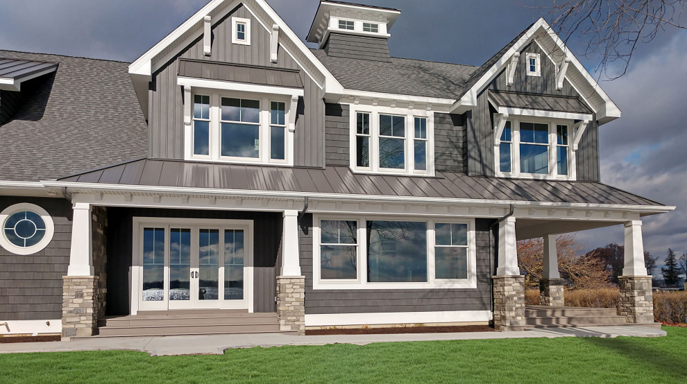 Photo of an arts and crafts two-storey grey house exterior in Other with vinyl siding, a gable roof and a mixed roof.