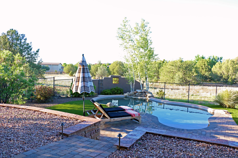 Photo of a large backyard custom-shaped pool in Phoenix with brick pavers.