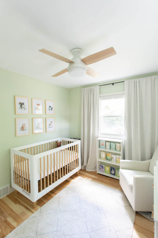 Aménagement d'une petite chambre de bébé neutre contemporaine avec un mur vert et parquet clair.