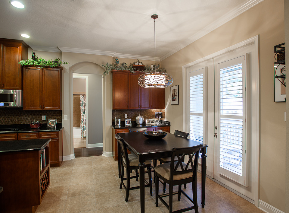 This is an example of a large traditional galley eat-in kitchen in Tampa with a drop-in sink, recessed-panel cabinets, dark wood cabinets, granite benchtops, brown splashback, mosaic tile splashback, stainless steel appliances, ceramic floors and with island.