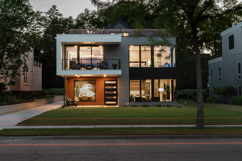 Inspiration pour une façade de maison grise minimaliste en bardage à clin de taille moyenne et à deux étages et plus avec un revêtement mixte, un toit à deux pans, un toit en shingle et un toit noir.