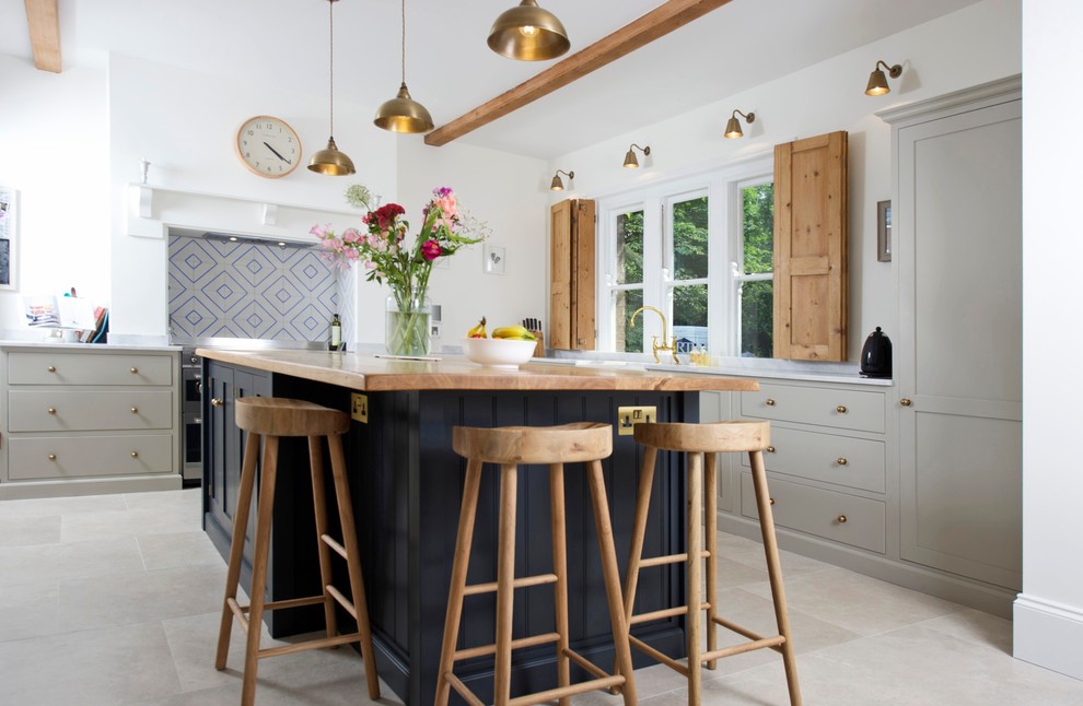 Mid-sized country l-shaped kitchen in Hertfordshire with an undermount sink, recessed-panel cabinets, grey cabinets, wood benchtops, white splashback, stainless steel appliances, with island, grey floor and beige benchtop.